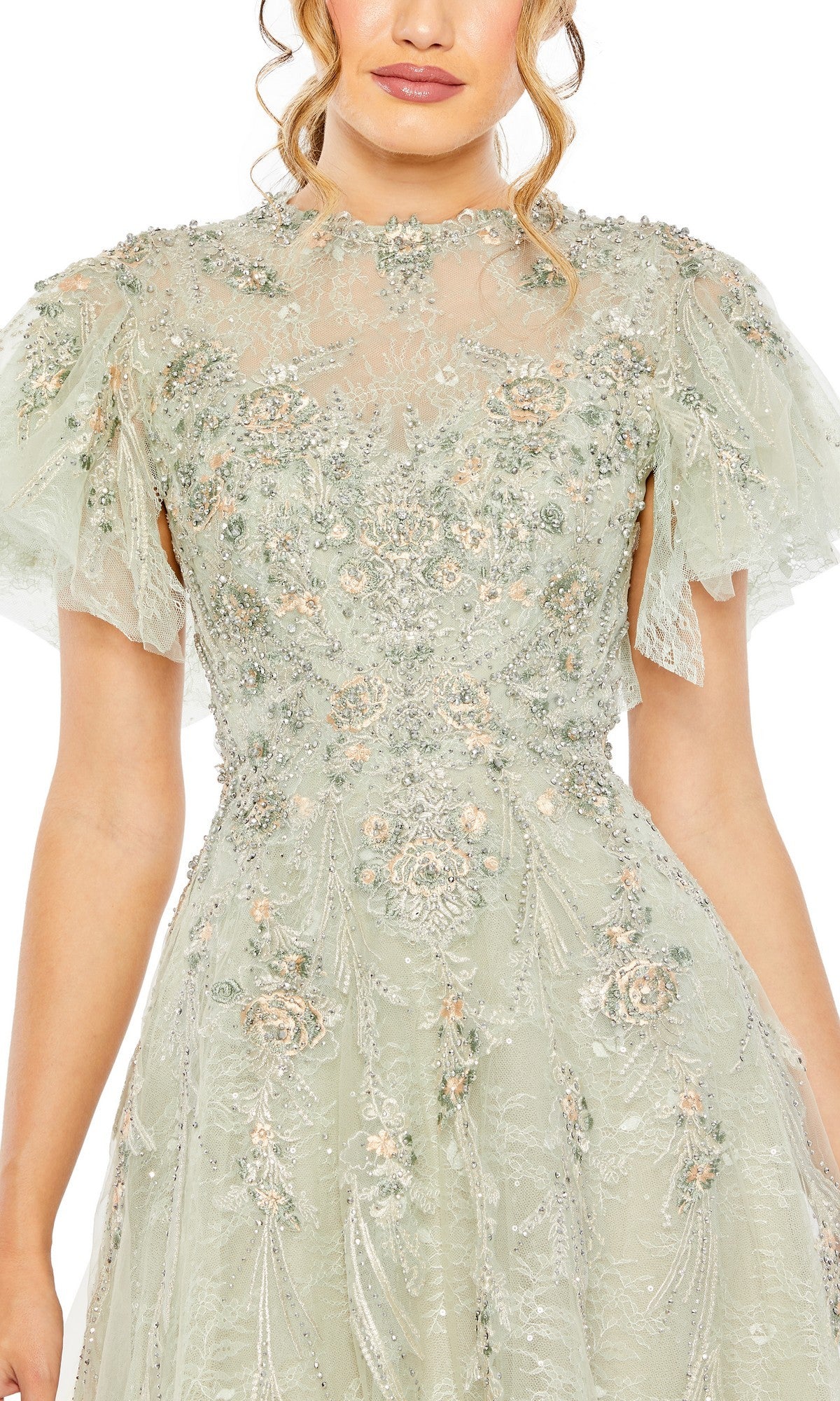 A woman wearing the Mac Duggal 20450 long formal dress in light green, featuring floral embroidery, lace accents, and short sheer sleeves.